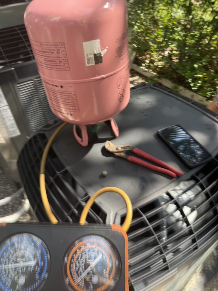Refrigerant cylinder and gauges connected during an AC repair
